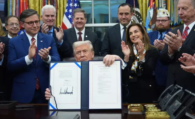 President Donald Trump displays the signed funding bill to reopen the government, in the Oval Office of the White House, Wednesday, Nov. 12, 2025, in Washington. (AP Photo/Jacquelyn Martin)