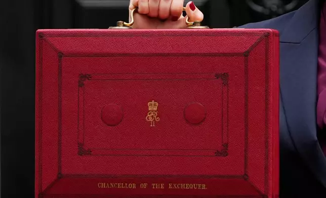 FILE - Britain's Chancellor of the Exchequer, Rachel Reeves, holds up the traditional red ministerial box containing her budget speech, as she poses for the media outside No 11 Downing Street, before departing to the House of Commons to deliver the budget in London, Wednesday, Oct. 30, 2024. (AP Photo/Kirsty Wigglesworth, File)