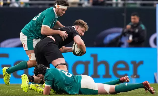 New Zealand's Fabien Holland is tackled by Ireland's Ryan Baird, bottom, and Finlay Bealham, left, during the rugby international between the All Blacks and Ireland in Chicago, Saturday, Nov. 1, 2025. (AP Photo/Erin Hooley)