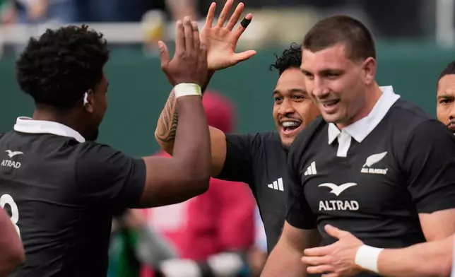 New Zealand's Leicester Fainga'anuku, centre, celebrates with teammate Peter Lakai, left, after their team's first try during the rugby international between the All Blacks and Ireland in Chicago, Saturday, Nov. 1, 2025. (AP Photo/Erin Hooley)
