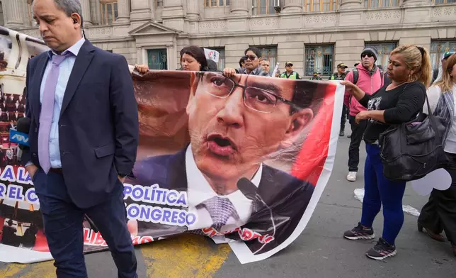 Supporters of former President Martin Vizcarra, who faces corruption charges, carry a banner featuring Vizcarra as they gather outside a courtroom in Lima, Peru, Wednesday, Nov. 26, 2025.(AP Photo/Martin Mejia)