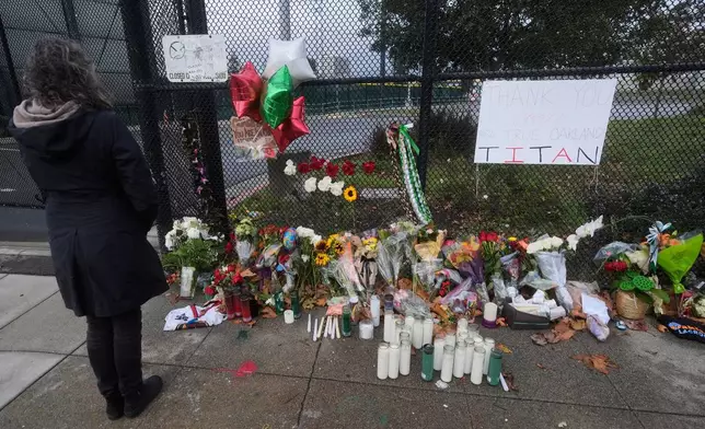Jayne Moser looks at a sidewalk memorial for former football coach John Beam at Laney College, in Oakland, Calif., Monday, Nov. 17, 2025. (AP Photo/Jeff Chiu)