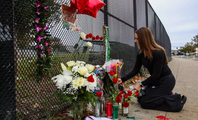 Leticia Palazzo contributes to a makeshift memorial outside the Laney College Athletics Fieldhouse for Athletic Director John Beam, who was shot Thursday, in Oakland, Calif., Saturday, Nov. 15, 2025. (Yalonda M. James/San Francisco Chronicle via AP)
