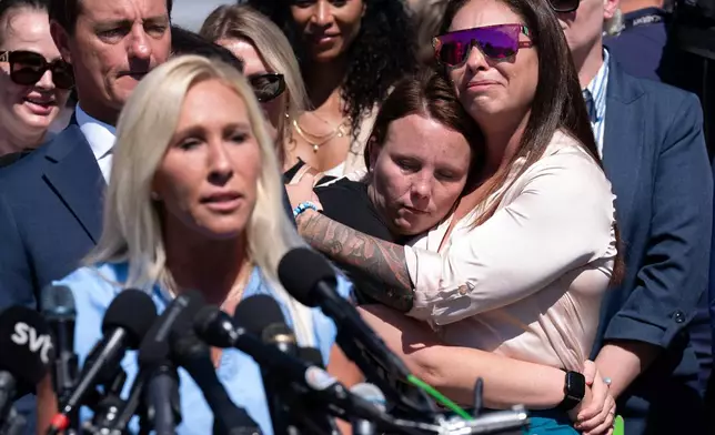 FILE - Jena-Lisa Jones, center, hugs Haley Robson, right, as Rep. Marjorie Taylor Greene, R-Ga., left, speaks during a news conference at the U.S. Capitol, Sept. 3, 2025, in Washington. (AP Photo/Jose Luis Magana, File)