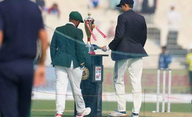 India's captain Shubman Gill, right, and South Africa's captain Temba Bavuma walk to pose with the trophy before the start of of the first day of the first cricket test match between India and South Africa in Kolkata, India, Friday, Nov. 14, 2025. (AP Photo/Aijaz Rahi)