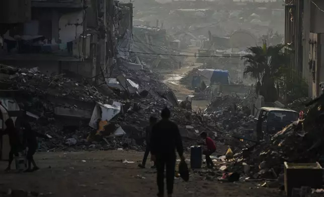 Palestinians walk through the destruction left by the Israeli air and ground offensive in Gaza City, Saturday, Nov. 29, 2025. (AP Photo/Abdel Kareem Hana)