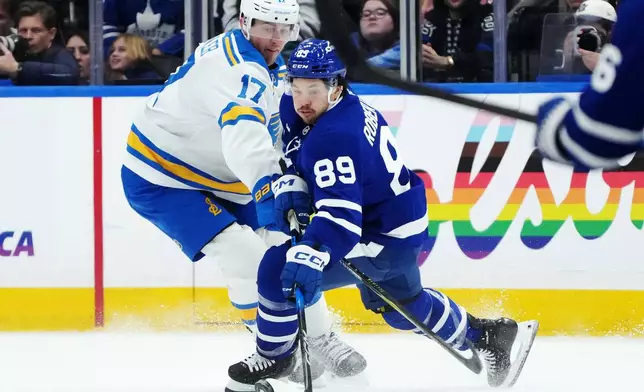 Toronto Maple Leafs' Nicholas Robertson (89) battles for the puck with St. Louis Blues' Cam Fowler (17) during the third period of an NHL hockey game in Toronto, Tuesday, Nov. 18, 2025. (Nathan Denette/The Canadian Press via AP)