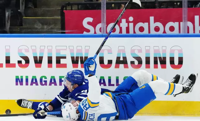 Toronto Maple Leafs' Troy Stecher, top, is taken down by St. Louis Blues' Pavel Buchnevich during the first period of NHL hockey in Toronto on Tuesday, Nov. 18, 2025. (Nathan Denette/The Canadian Press via AP)