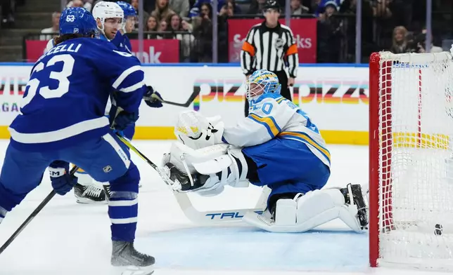 St. Louis Blues goaltender Jordan Binnington (50) is scored on as Toronto Maple Leafs' Matias MacCelli (63) looks on during second period NHL hockey in Toronto on Tuesday, Nov. 18, 2025. (Nathan Denette/The Canadian Press via AP)
