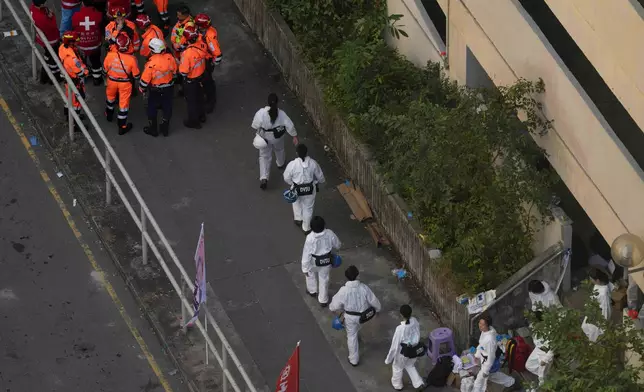 Members of the Disaster Victims Identification Unit walks to the site of a Wednesday fire at Wang Fuk Court, a residential estate in the Tai Po district of Hong Kong's New Territories, Friday, Nov. 28 2025. (AP Photo/Ng Han Guan)