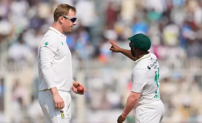 South Africa's Simon Harmer, left, listens to captain Temba Bavuma before bowling his next delivery on the second day of the first cricket test match between India and South Africa in Kolkata, India, Saturday, Nov. 15, 2025. (AP Photo/Aijaz Rahi)