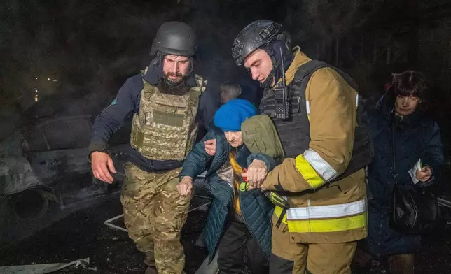 Rescuers evacuate an elderly woman after a residential building was hit following Russia's missile attack in Kharkiv, Ukraine Wednesday, Nov. 19, 2025. (AP Photo/Andrii Marienko)