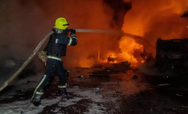 Rescue workers put out a fire of a residential building damaged by a Russian strike on Kharkiv, Ukraine, Wednesday, Nov. 19, 2025. (AP Photo/Andrii Marienko)