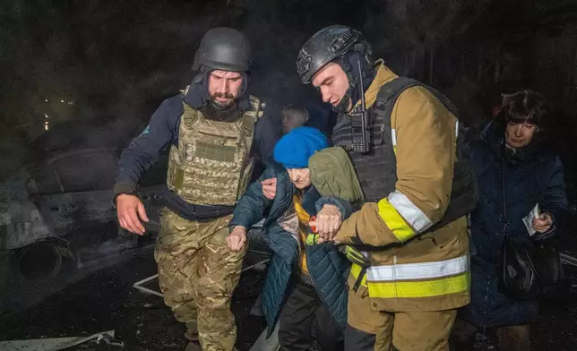 Rescuers evacuate an elderly woman after a residential building was hit following Russia's missile attack in Kharkiv, Ukraine Wednesday, Nov. 19, 2025. (AP Photo/Andrii Marienko)