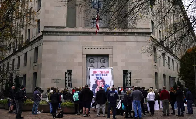 FILE - Advocates for opioid victims gather around a banner made by artist Fernando Luis Alvarez during a protest outside the Department of Justice, Dec. 3, 2021, in Washington. (AP Photo/Carolyn Kaster, File)