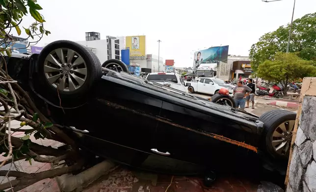 A man stands behind a damaged car following floods in Songkhla province, southern Thailand, Friday, Nov. 28, 2025. (AP Photo/Sarot Meksophawannakul)
