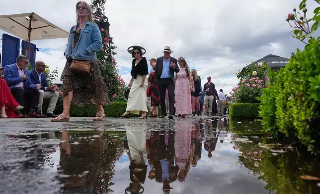 Spectators walk ahead of the Melbourne Cup horse race in Melbourne, Australia, Tuesday, Nov. 4, 2025. (AP Photo/Asanka Brendon Ratnayake)