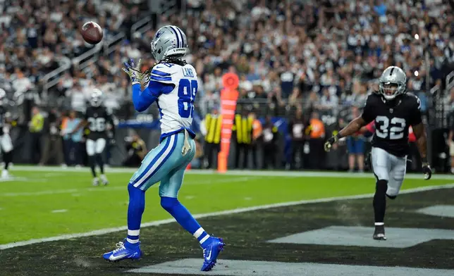 Dallas Cowboys wide receiver CeeDee Lamb (88) reaches out to make a touchdown catch as Las Vegas Raiders safety Lonnie Johnson Jr. (32) looks on during the first half of an NFL football game Monday, Nov. 17, 2025, in Las Vegas. (AP Photo/John Locher)