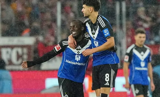 Hamburg's Jean-Luc Dompe, left, celebrates after scoring his side's opening goal during the German Bundesliga soccer match between Cologne and Hamburger SV, in Cologne, Germany, Sunday, Nov. 2, 2025. (AP Photo/Martin Meissner)