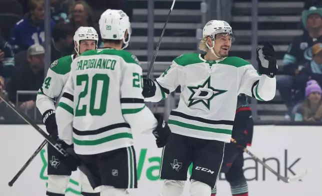 Dallas Stars center Roope Hintz, right, celebrates with defenseman Kyle Capobianco (20) and left wing Jamie Benn (14) after scoring during the first period of an NHL hockey game against the Seattle Kraken Wednesday, Nov. 26, 2025, in Seattle. (AP Photo/Jason Redmond)