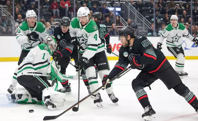 Seattle Kraken center Shane Wright (51) tries to score as Dallas Stars goalie Casey DeSmith (1) and defenseman Miro Heiskanen (4) defend during the first period of an NHL hockey game Wednesday, Nov. 26, 2025, in Seattle. (AP Photo/Jason Redmond)