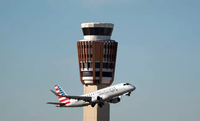 An American Airlines American Eagle jet flies past the air traffic control tower at Phoenix Sky Harbor International Airport Saturday, Nov. 8, 2025, in Phoenix. (AP Photo/Ross D. Franklin)