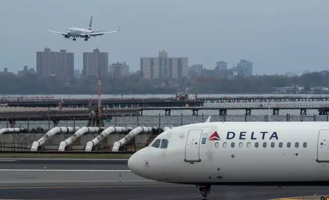 An American Airlines flight lands as a Delta Air Lines plane taxis at LaGuardia Airport (LGA) in the Queens borough of New York, Sunday, Nov. 9, 2025. (AP Photo/Adam Gray)