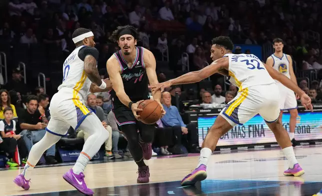 Miami Heat forward Jaime Jaquez Jr. (11) drives to the basket as Golden State Warriors guard Gary Payton II (0) and forward Trayce Jackson-Davis (32)defend during the first half of an NBA basketball game, Wednesday, Nov. 19, 2025, in Miami. (AP Photo/Lynne Sladky)