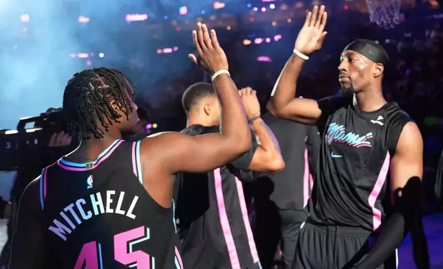 Miami Heat center Bam Adebayo, right, greets guard Davion Mitchell (45) before an NBA basketball game against the Golden State Warriors, Wednesday, Nov. 19, 2025, in Miami. (AP Photo/Lynne Sladky)