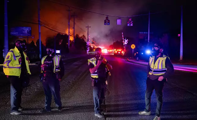Members of law enforcement wear respirators near the area of the reported plane crash at Louisville Muhammad Ali International Airport on Tuesday, Nov. 4, 2025, in Louisville, Ky. (AP Photo/Jon Cherry)