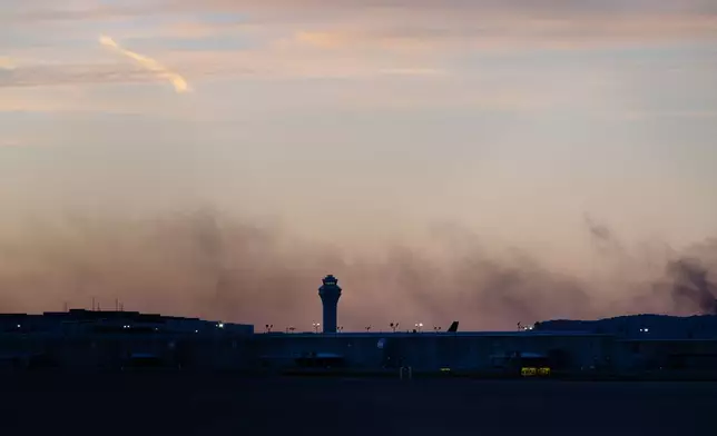 The ATC tower is seen while smoke rises from the crash site of UPS Flight 2796 near Louisville Muhammad Ali International Airport on Wednesday, Nov. 5, 2025, in Louisville, Ky. (AP Photo/Jon Cherry)