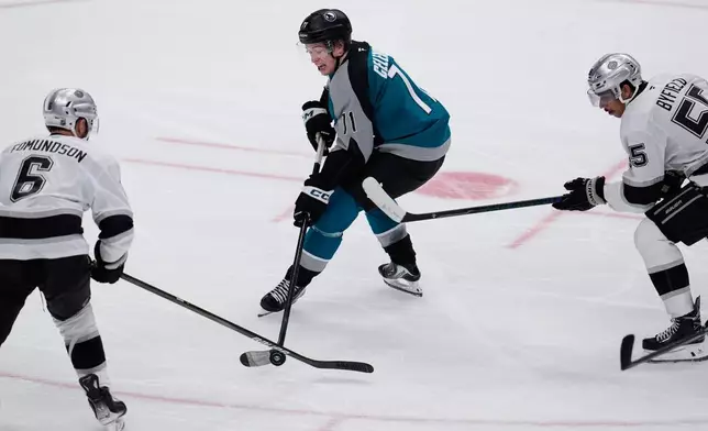 San Jose Sharks center Macklin Celebrini (71) moves the puck between Los Angeles Kings defenseman Joel Edmundson (6) and right wing Quinton Byfield (55) during the second period of an NHL hockey game, Thursday, Nov. 20, 2025, in San Jose, Calif. (AP Photo/Godofredo A. Vásquez)