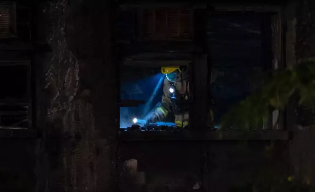 A firefighter searches through a building in the aftermath of a fire at Wang Fuk Court, a residential estate in the Tai Po district of Hong Kong's New Territories, Thursday, Nov. 27 2025. (AP Photo/Ng Han Guan)
