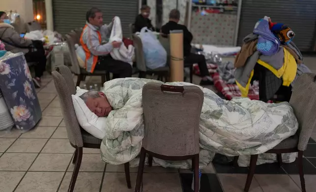 A man rests on a makeshift bed made up of chairs at a nearby shopping mall where residents are taking shelter in the aftermath of the fire at Wang Fuk Court, a residential estate in the Tai Po district of Hong Kong's New Territories, Thursday, Nov. 27 2025. (AP Photo/Ng Han Guan)