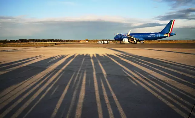 Reporters' shadows are cast on the tarmac as they wait for the plane to depart that is transporting Pope Leo XIV to a six-day trip to Turkey and Lebanon, at the Fiumicino airport in Rome, Thursday, Nov. 27, 2025. (AP Photo/Alessandra Tarantino)