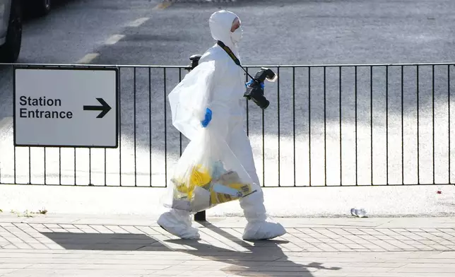 A forensic investigator carries evidence after a mass stabbing on a London-bound train at a train station in Huntingdon, England, Sunday, Nov. 2, 2025.(AP Photo/Kirsty Wigglesworth)