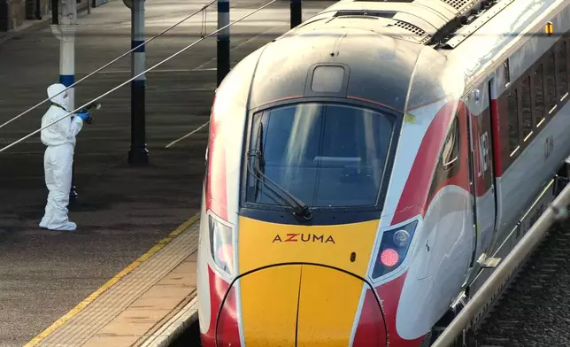 A forensic investigator takes pictures of the train after a mass stabbing on a London-bound train in Huntingdon, England, Sunday, Nov. 2, 2025.(AP Photo/Kirsty Wigglesworth)