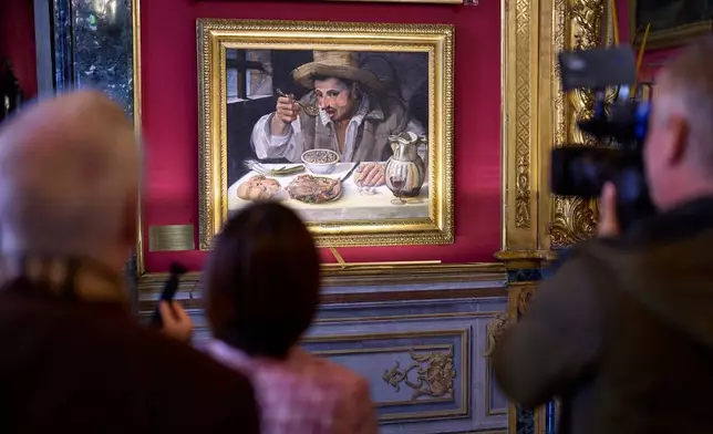 Journalists film Annibale Carracci's oil-on-canvas painting The Bean Eater, on display at Palazzo Colonna, or the Colonna Palace, in Rome during a media tour, Friday, Nov. 7, 2025. (AP Photo/Domenico Stinellis)