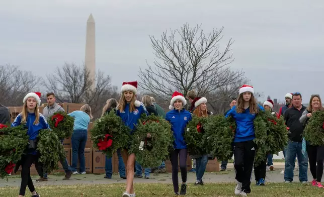 FILE - Volunteers walk with holiday wreaths to lay at headstones in Arlington National Cemetery during Wreaths Across America Day in Arlington, Va., Dec. 18, 2021. (AP Photo/Gemunu Amarasinghe, File)