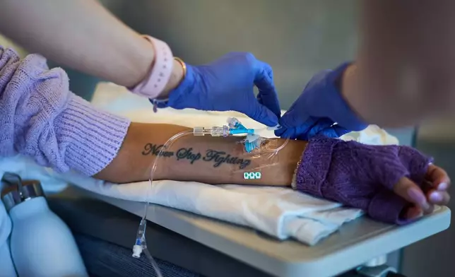A tattoo reading "Never Stop Fighting" decorates the arm of Ruth Wilson, as she receives her monthly lupus-focused IV treatment at UMass Memorial Medical Center, Tuesday, Jan. 14, 2025, in Worcester, Mass. (AP Photo/David Goldman)