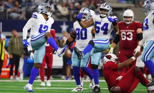 Dallas Cowboys' Dante Fowler Jr. (13) and Sam Williams (54) celebrate after sacking Arizona Cardinals' Jacoby Brissett, bottom right, in the second half of an NFL football game Monday, Nov. 3, 2025, in Arlington, Texas. (AP Photo/Richard Rodriguez)