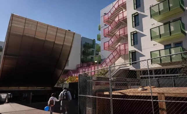 A family arrives at a metro station next to the Santa Monica and Vermont Apartments in Los Angeles, Monday, Nov. 10, 2025. (AP Photo/Jae C. Hong)