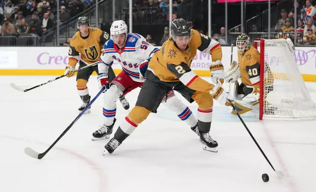 Vegas Golden Knights defenseman Zach Whitecloud (2) skates with the puck against New York Rangers left wing Will Cuylle (50) during the first period of an NHL hockey game Tuesday, Nov. 18, 2025, in Las Vegas. (AP Photo/Candice Ward)