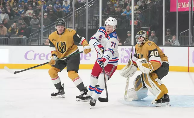 New York Rangers center Juuso Parssinen (71) reaches for the puck in from of Vegas Golden Knights defenseman Kaedan Korczak (6) and goaltender Akira Schmid (40) during the first period of an NHL hockey game Tuesday, Nov. 18, 2025, in Las Vegas. (AP Photo/Candice Ward)