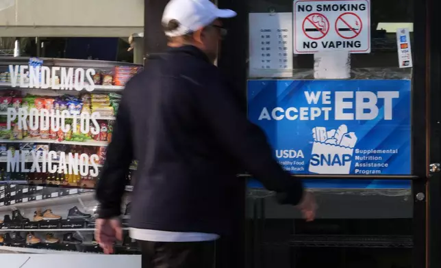 A customer walks into a bakery as a SNAP EBT information sign is displayed at the front door in Chicago, Sunday, Nov. 2, 2025. (AP Photo/Nam Y. Huh)