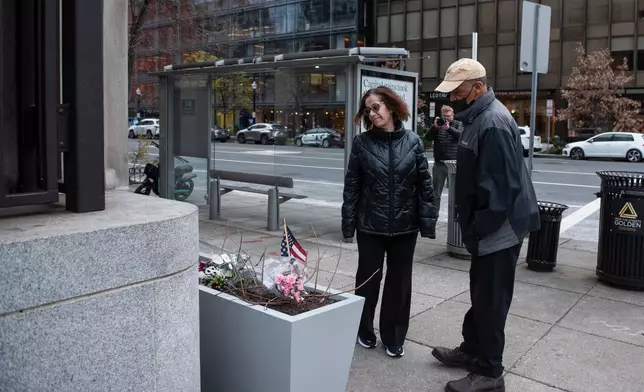 At the scene of the shooting, a couple looks at a memorial a day after two National Guard soldiers were shot near the White House in Washington, Thursday, Nov. 27, 2025. (AP Photo/Cliff Owen)
