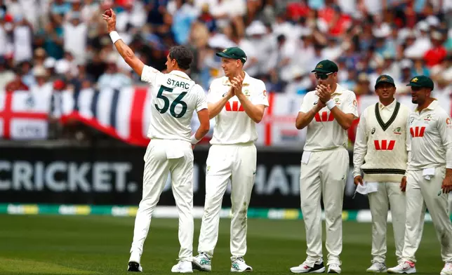 Australia's Mitchell Starc, left, lifts the ball to acknowledge his tenth wicket in the first Ashes cricket test match between Australia and England in Perth, Saturday, Nov. 22, 2025.(AP Photo/Gary Day)