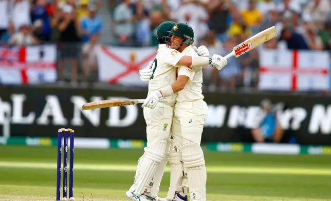 Australia's Travis Head, left, is hugged by batting partner Marnus Labuschagne after the former got out on day two of the first Ashes cricket test match between Australia and England in Perth, Saturday, Nov. 22, 2025.(AP Photo/Gary Day)