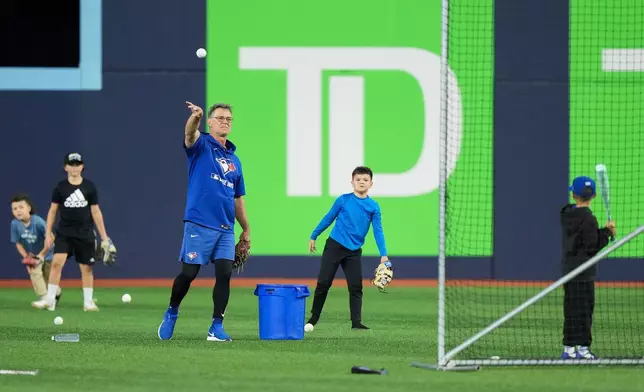 Toronto Blue Jays bench coach Don Mattingly, third from right, pitches with children on the field during World Series baseball workouts in Toronto, Thursday, Oct. 30, 2025. (Nathan Denette/The Canadian Press via AP)