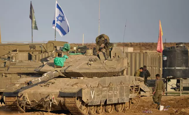 Israeli soldiers work on tanks at a staging area on the border with Gaza Strip, in southern Israel, Tuesday, Nov. 18, 2025. (AP Photo/Ohad Zwigenberg)